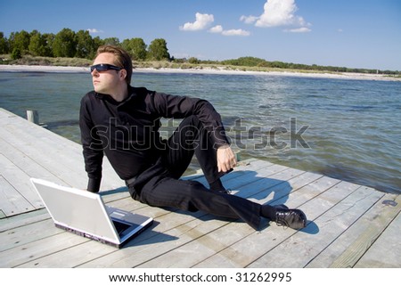 Business man with his laptop while sitting on the pier and getting inspiration