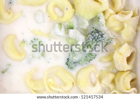 Looking down at a frozen tortellini with, alfredo sauce dinner.