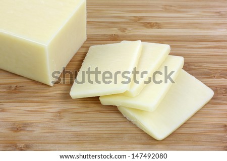 A close view of a block of reduced fat cheese and slices.