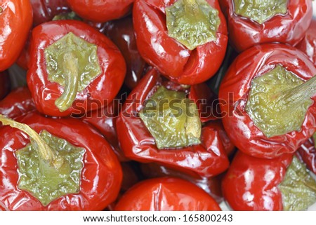 A close top view of small red cherry peppers with large green  curved stems.