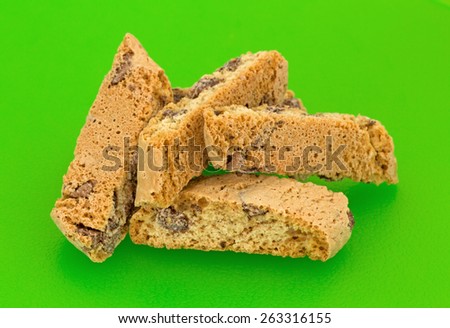 A group of four slices of Cantuccini biscuits with chocolate chips  on a bright green cutting board.