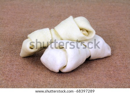 Two white rawhide dog bones on brown cloth.