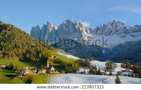 Image of two photos taken two days after one another showing the change of season from fall to winter. The village of St. Magdalena in front of dolomites mountain peaks in the Val di Funes in Italy.