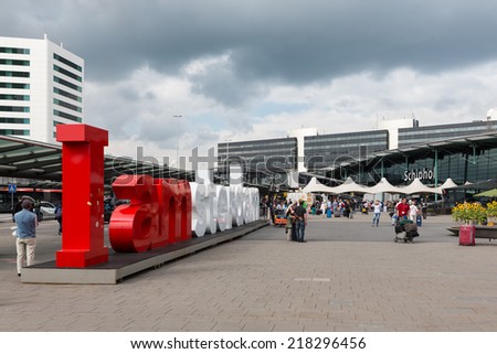 AMSTERDAM, THE NETHERLANDS - SEP 11: Airport square with Amsterdam logo and unknown travellers on September 11, 2014 at the airport Schiphol of Amsterdam, the Netherlands