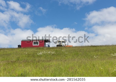 Silhouette of tractor with house trailer upon a hill against a blue sky