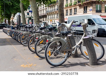 PARIS, FRANCE - May 29: Street view with unknown woman paying for renting a bicycle on May 29, 2015, Paris, France