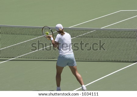 Tennis player performing a backhand volley at the net