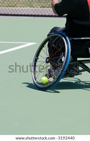 A wheelchair bound athlete on the tennis court - showing the angle of the wheel and the tennis ball being held in