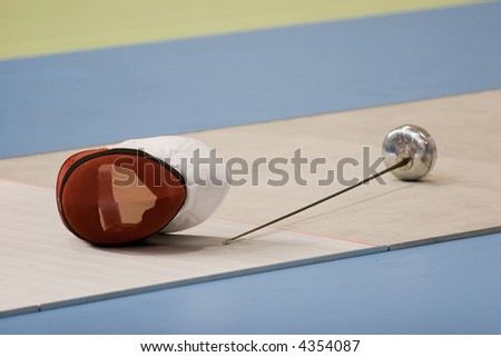 A fencing mask and a fencing sword on the floor
