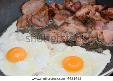 Bacon and eggs being cooked in a frying pan