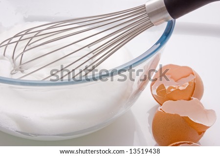 Egg whisk in a bowl with Egg whites and broken egg shells