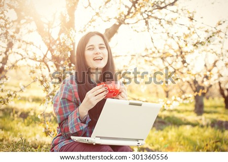Portrait of a beautiful brunette women with notebook in blossom apple tree garden in spring time on sunset.
