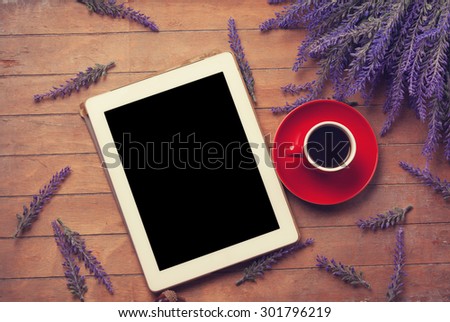Tablet with coffee on the wooden table