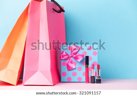 makeup cosmetics and gift box with shopping bags on blue background