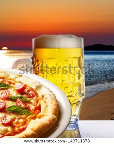 Pizza with a glass of beer  on a beach