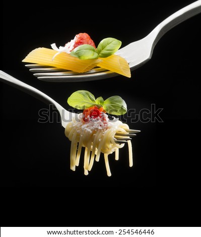 forks with macaroni spaghetti and tomato sauce on dark background