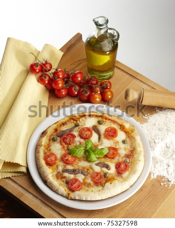 pizza with a bottle of olive oil and tomatoes on a white background