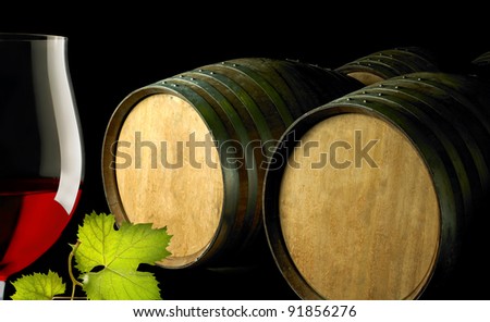 red wine glass and barrels on black background