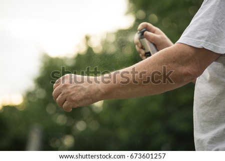 Senior man hands spraying mosquito / insect repellent in the forest