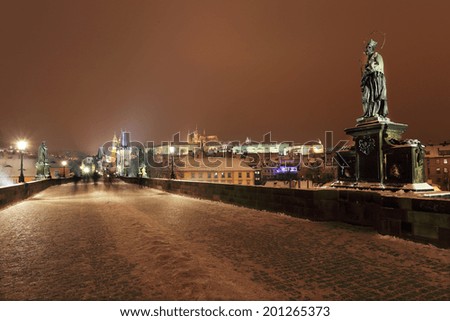 Night romantic colorful snowy Prague gothic Castle, Bridge Tower and St. Nicholas\' Cathedral from Charles Bridge, Czech republic