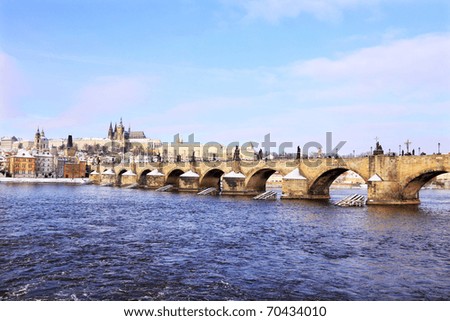 Romantic Snowy Prague gothic Castle with the Charles Bridge in the sunny Day