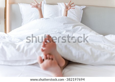 Close-up of a person\'s feet and hand sleeping on bed.