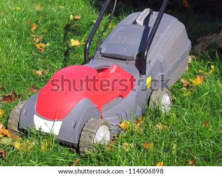 Modern electric lawn mower on the unmown lawn