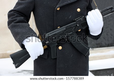 White gloves hands of a honor guard holding a Kalashnikov submachine gun (AK-47)