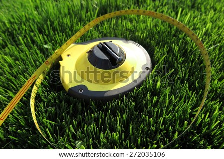 Measuring tape lying on the fresh mow lawn grass in the summer garden