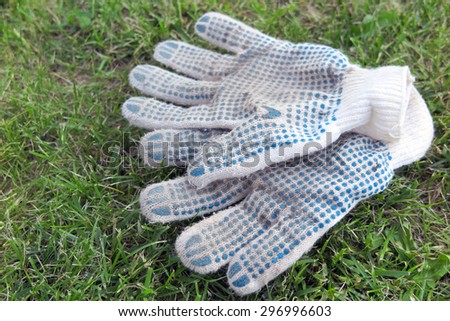 Cotton knitted work gloves lying on the mown lawn in the garden