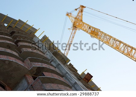 Building tower crane in action against a blue sky