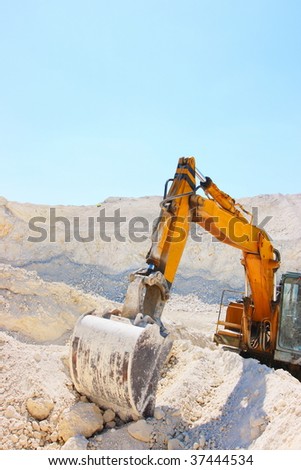 Caterpillar excavator in chalk pit against a blue sky