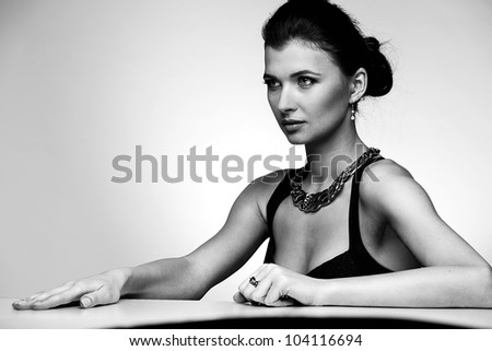 Black and white portrait of luxury woman in exclusive jewelry and black dress on natural background