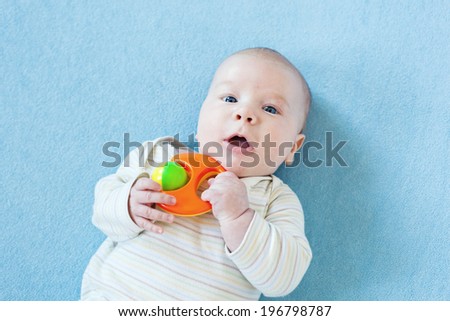 Portrait of Baby boy playing rattle under the blue blanket