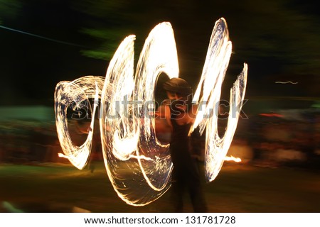 Fire dancer at night, in front of blurred background.