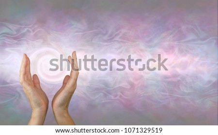 Channeling Vortex healing energy  - female hands held parallel with a white spiralling vortex energy formation and pale pink blue grey misty ethereal energy field background with copy space