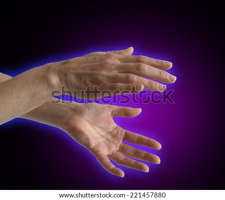 Healing Hands Aura - Healer\'s outstretched hands sensing energy on a black background showing electromagnetic energy field