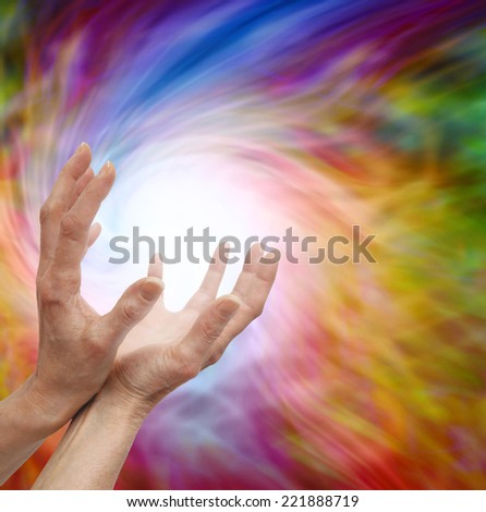 Female healer\'s outstretched cupped hands on colorful vortex swirling energy background