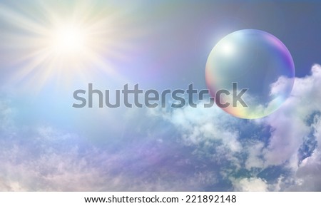 Blue sky with fluffy delicately color tinted clouds and a vibrant sunburst on left side with a large rainbow colored transparent bubble on right side
