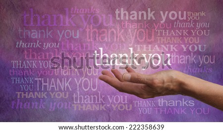 Giving Thanks - Female hand outstretched with palm up and the word \'Thank you\' hovering above with a stone effect purple and pink background covered in different colored and sized \'Thank yous\'