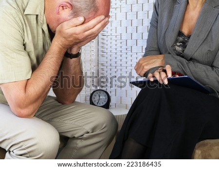 Female counselor with distressed male patient holding head in hands seated