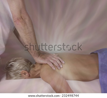 Energy Transfer during massage   -  Male massage therapist working on female client\'s upper back with energy emitting from hands