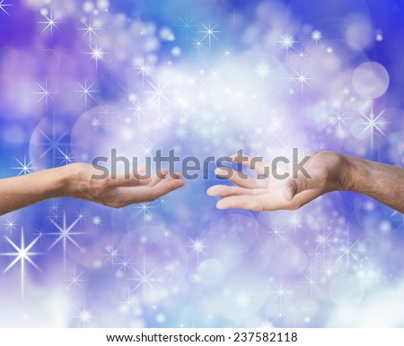 Soul mates sharing energy    Man and woman both with one hand outstretched towards each other palm up with an arc of white light and sparkles joining them on a blue colored energy formation background