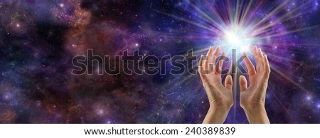 The Creative Spark - Female hands reaching up to a white burst of light on a wide deep space background with plenty of copy space on left hand side