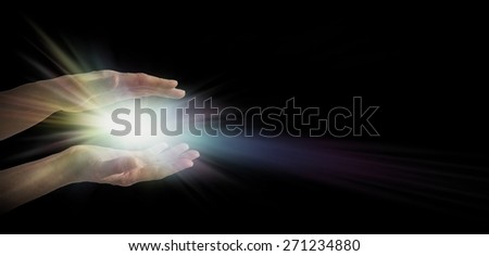 Light worker - pair of female hands emerging from the darkness with an explosion of white and rainbow tinted light energy between parallel hands