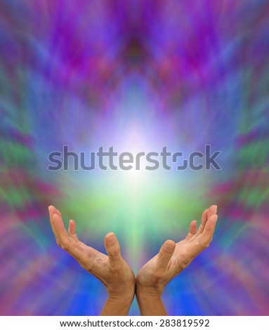 Sending Distant Healing - Healer\'s open hands sending distant healing with light white energy formation above on a multicolored background and plenty of copy space