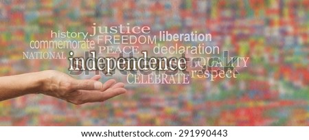 National Independence Day Banner - female\'s open palm with the word \'independence\' above surrounded by relevant word cloud on a stone effect background and blurred colors depicting flags of the world