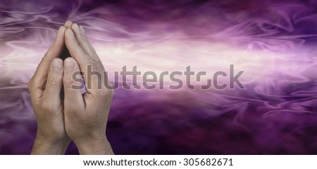 Cupped Hands in Prayer Position -  Male hands cupped together in prayer position on a dark purple and light pink energy streaming graduated background with plenty of copy space on the right hand side