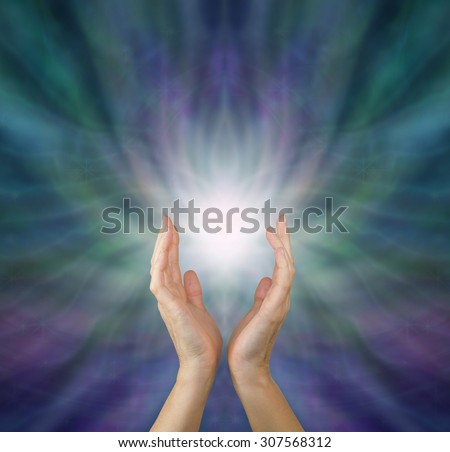 Sensing  Healing Energy - Female healing hands reaching up to white light emerging from radiating green and purple ethereal energy formation background with copy space above.
