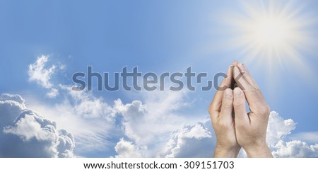 Cupped Hands in Prayer Position -  Male hands cupped together in prayer position on a wide sunny blue sky background with beautiful cloud formations and plenty of copy space on the left   side